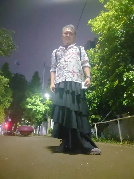 ロングスカート姿で夜道に立つ吉岡直哉
